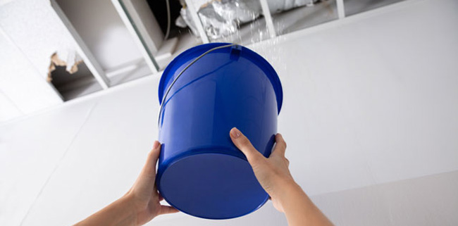 Secchio blu usato per racchogliere le perdite d'acqua del soffito